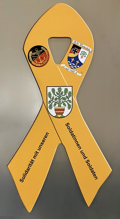 Gelbes Solidaritätsband mit Wappen und Schriftzug „Solidarität mit unseren Soldatinnen und Soldaten“.
